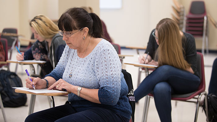 An adult student taking a test in a classroom along with other students