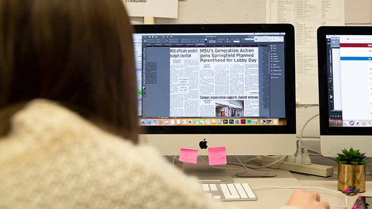 Student works at computer designing newspaper copy