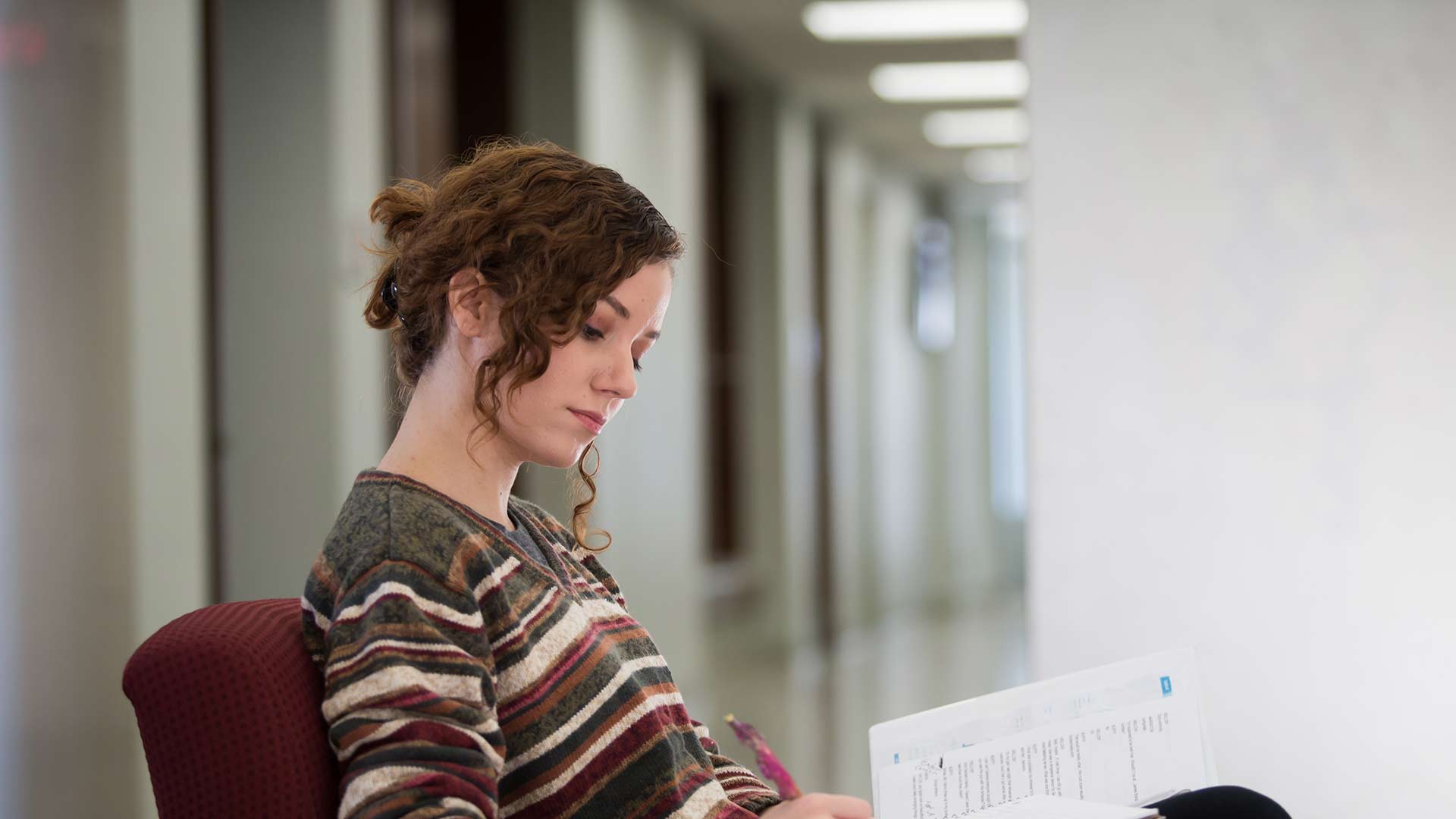 Student taking notes in hallway.