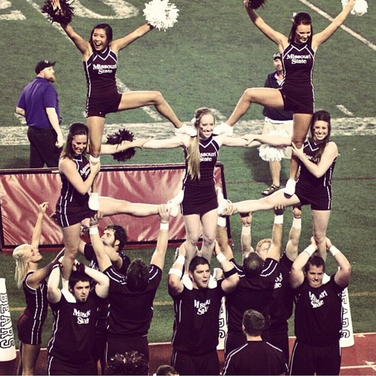 Cheerleaders perform stunts at a football game