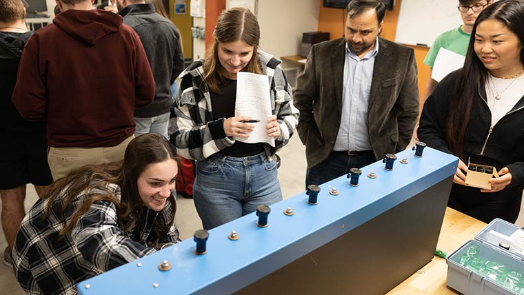 Dr. Sanjay Tewari guiding three students through lab exercise during class.