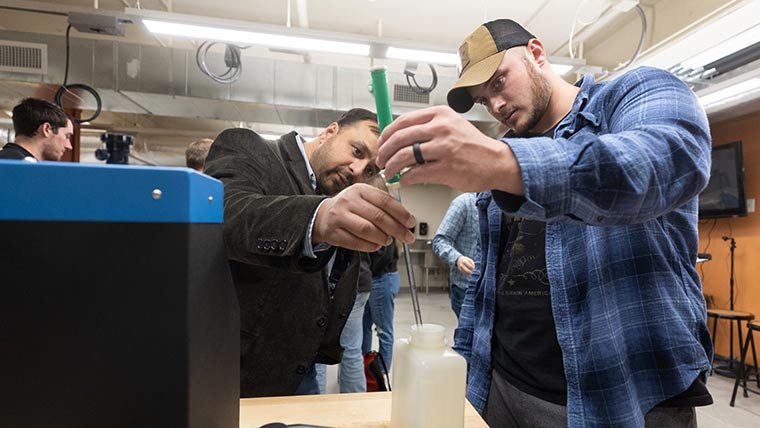 Dr. Sanjay Tewari and a student look holding a needle to take water measurements.