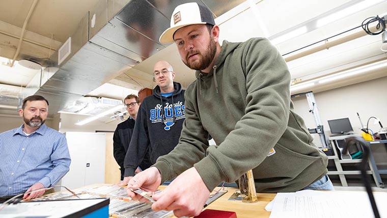 Dr. Jeff Thomas watches a student take measurements during a lab exercise while other students watch.