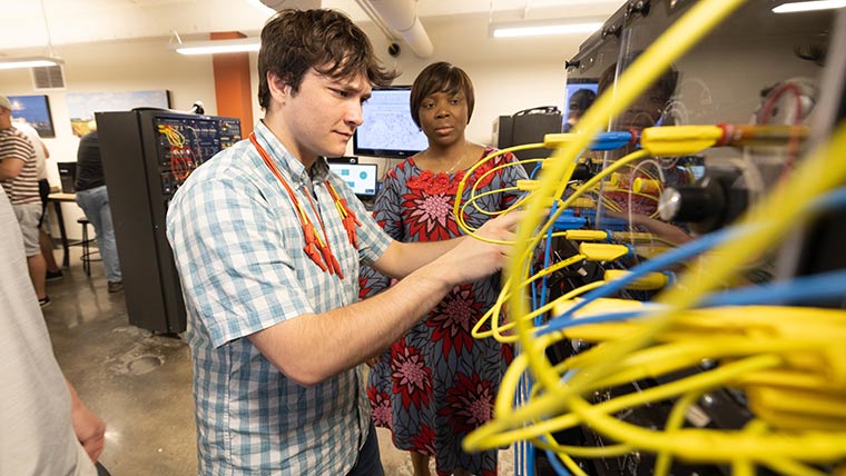 Dr. Theresa Odun-Ayo watches a student connect wiring during a lab exercise.