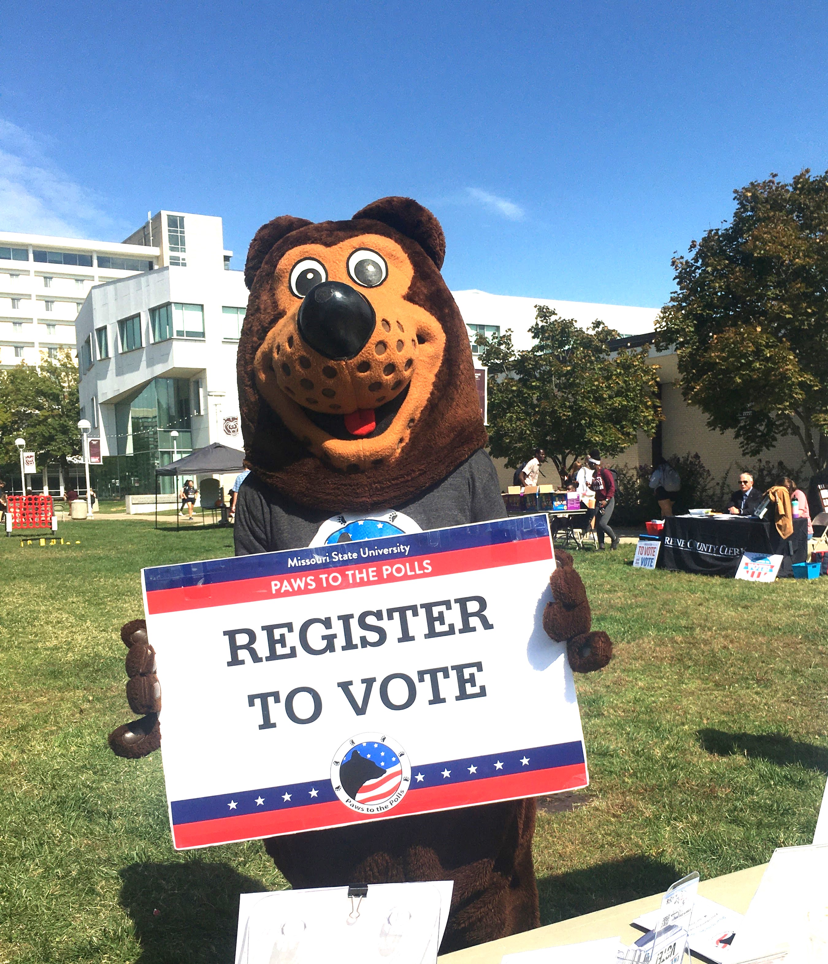 Picture of 'Boomer' the bear holding up a register for vote sign.