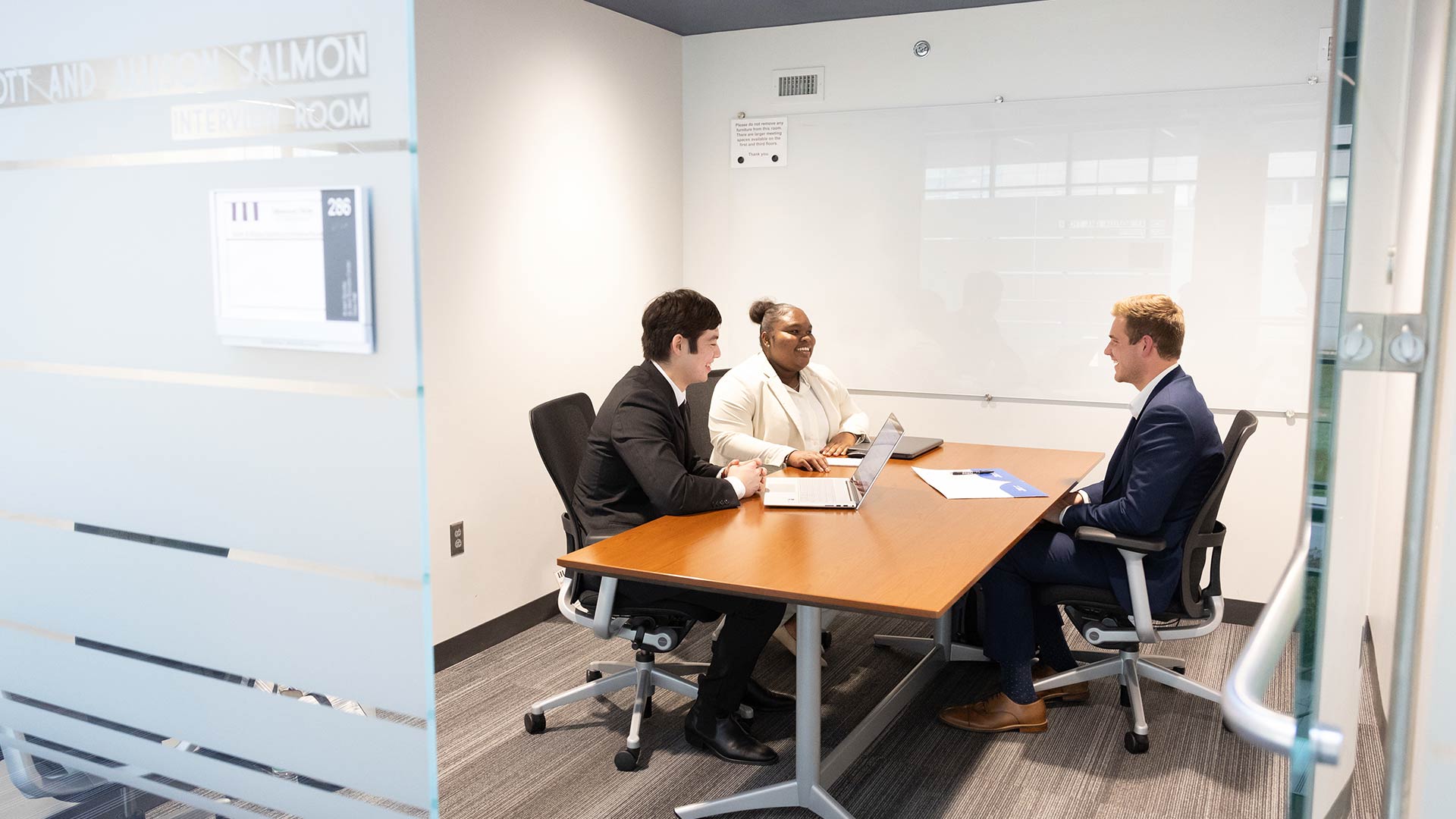 Looking into a conference room in Glass Hall where two financial planning students from Bear Essentials are meeting with a client.