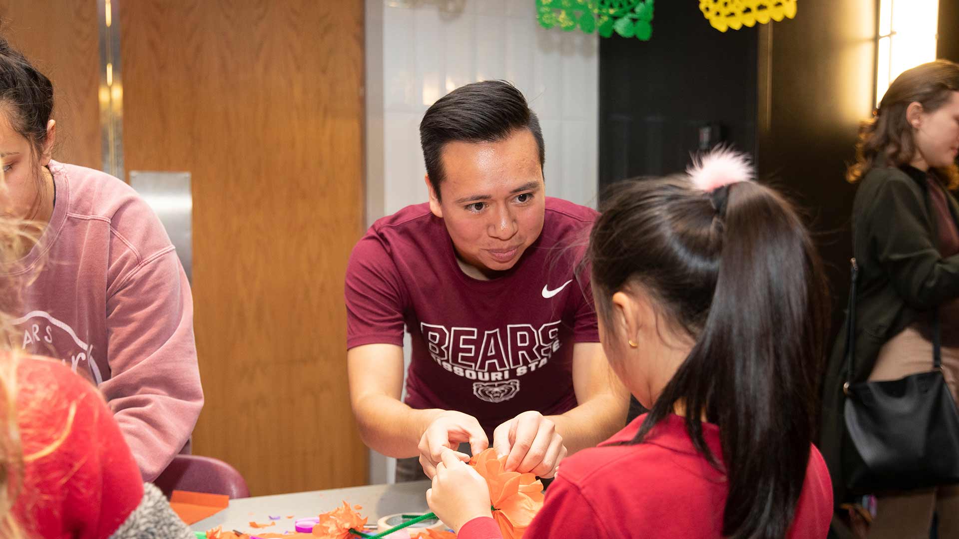 A Missouri State student interacts with a young child during a campus event for Day of the Dead celebration.