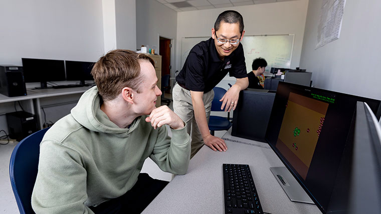 Professor assisting a Missouri State student within a computer lab.