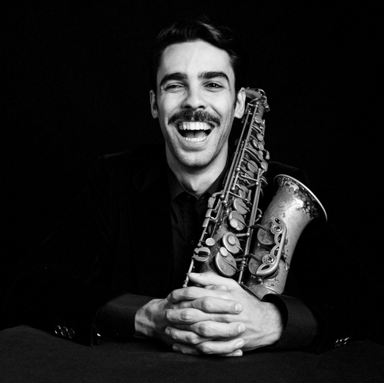 Photo of Eddie Barbash hugging saxophone