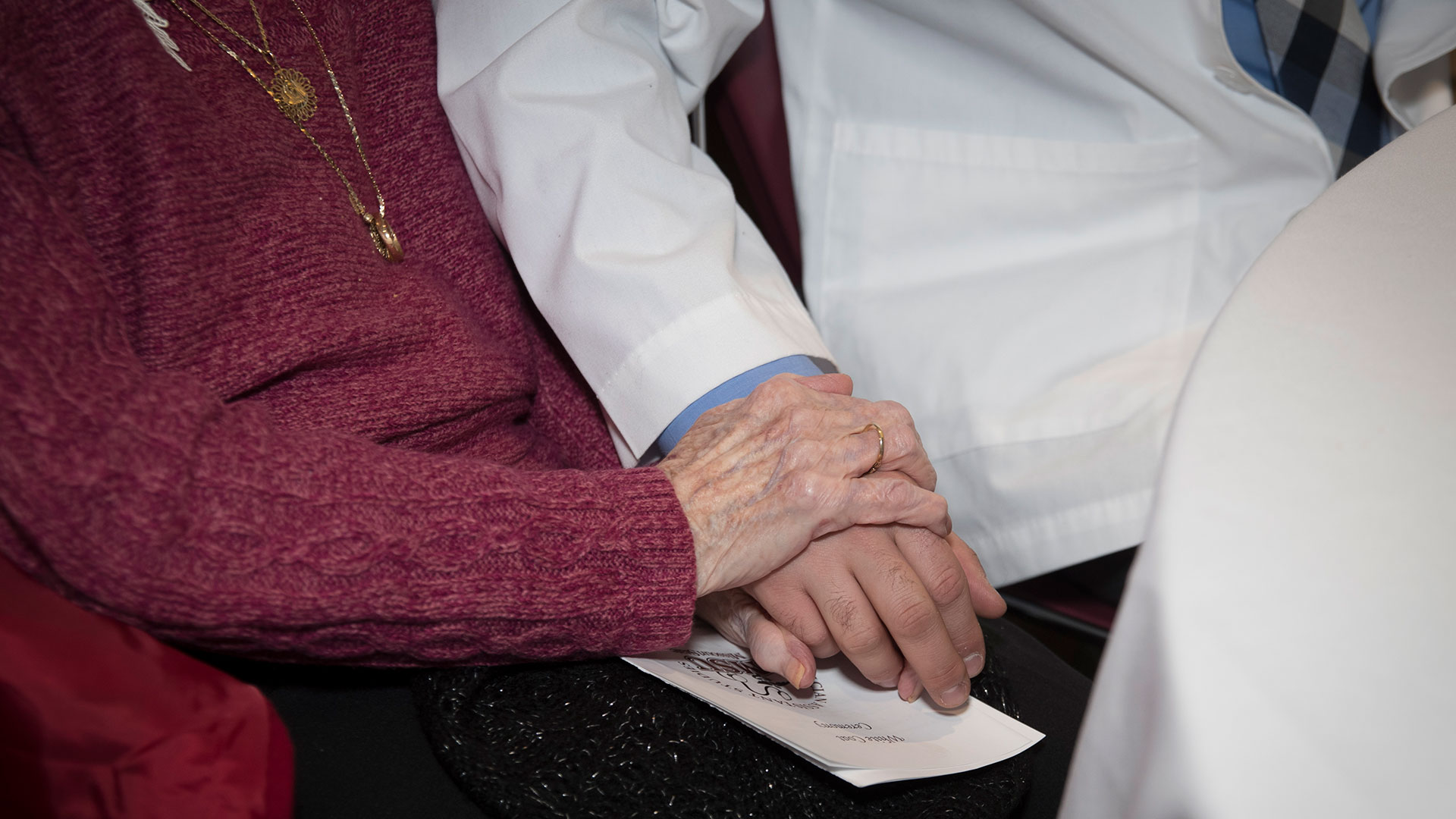 A student holds a woman's hand during the Physician Assistant White Coat Ceremony.