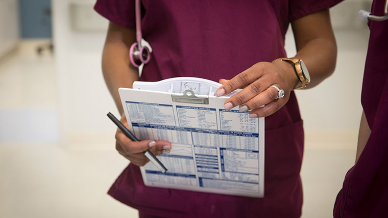 A student analyzes a patient's medical report on a clipboard.