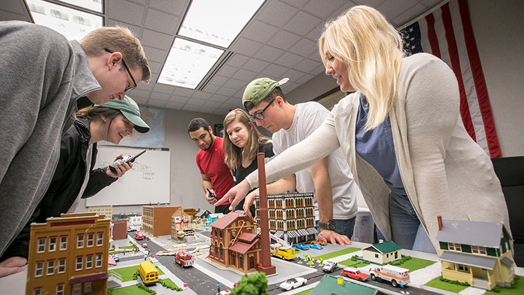 A classroom of MSU students discussing a model of a city. 