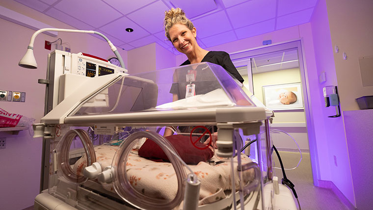 Ashlea Cardin stands beside a baby incubator in the NICU.