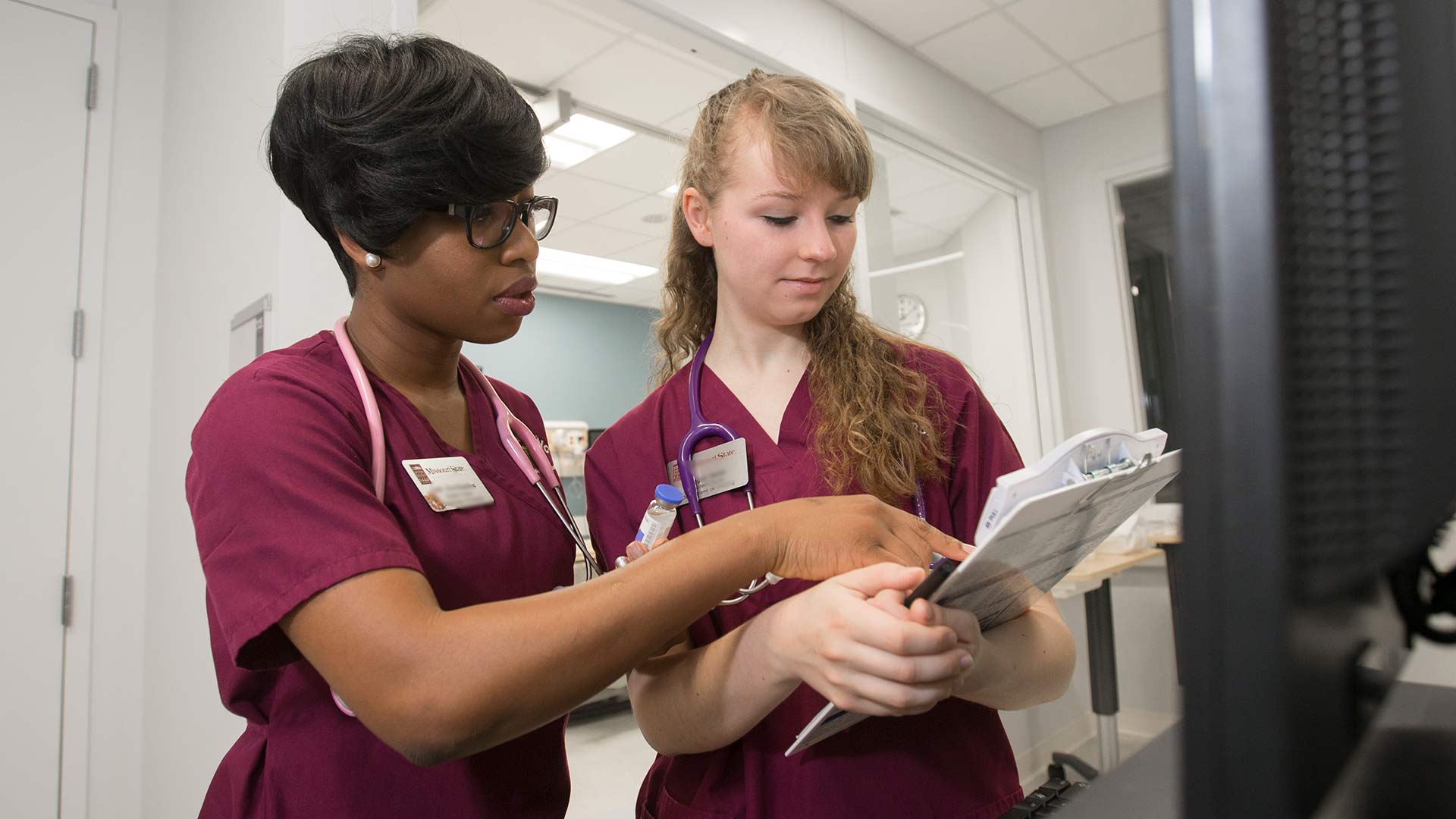 Two Missouri State nursing students going over paperwork in a nursing clinic on campus.
