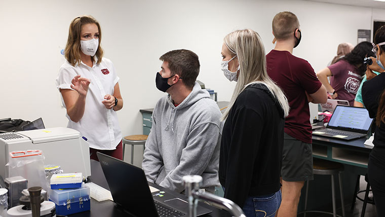 Dr. Randi J. Ulbricht, an assistant professor in biomedical sciences, instructing two students during a lab class.