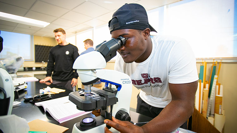 Student looking through a microscope.