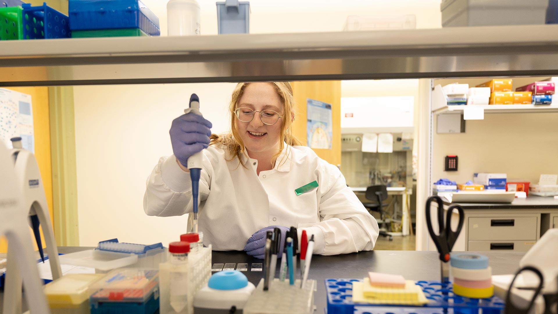 Science student in a white lab coat working in a research lab.