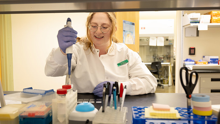 Science student in a white lab coat working in a research lab.