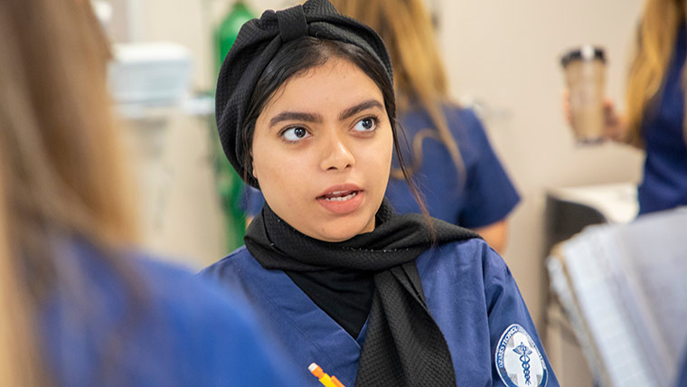 Health care student taking notes during a lab class.