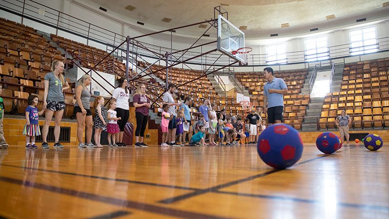 Kinesiology professor Junyoung Kim and his class prepare for an activity with children in a gymnasium.