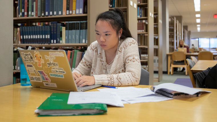 Student using laptop in library.