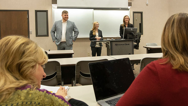 Three students presenting to a class.