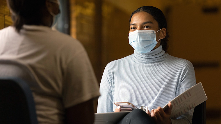 Student wearing a mask and holding a clipboard.