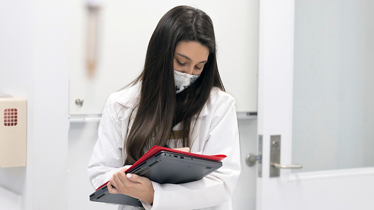 Student in a white lab coat charting