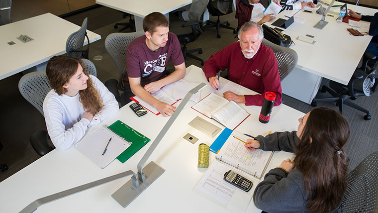 An MSU professor leads three accounting students in a study group session. The students listen intently with their notebooks in front of them.