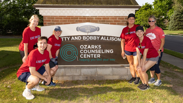 Six volunteers standing by the Ozarks Counseling Center sign.