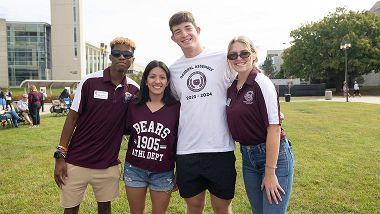 Four students pose for a photo at Bearfest Village during Family Weekend.