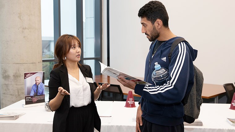 An admissions rep talks to a prospective student during an open house event for the College of Business.