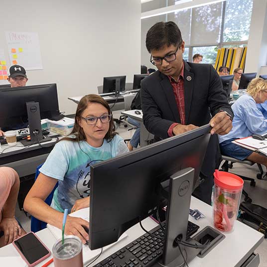 Dr. Razib Iqbal, a computer science professor, assists a CODERS student with a project on the computer