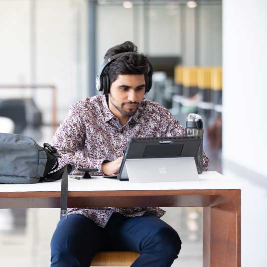 Kamran Choudhry uses his headphones and tablet to study in Glass Hall.