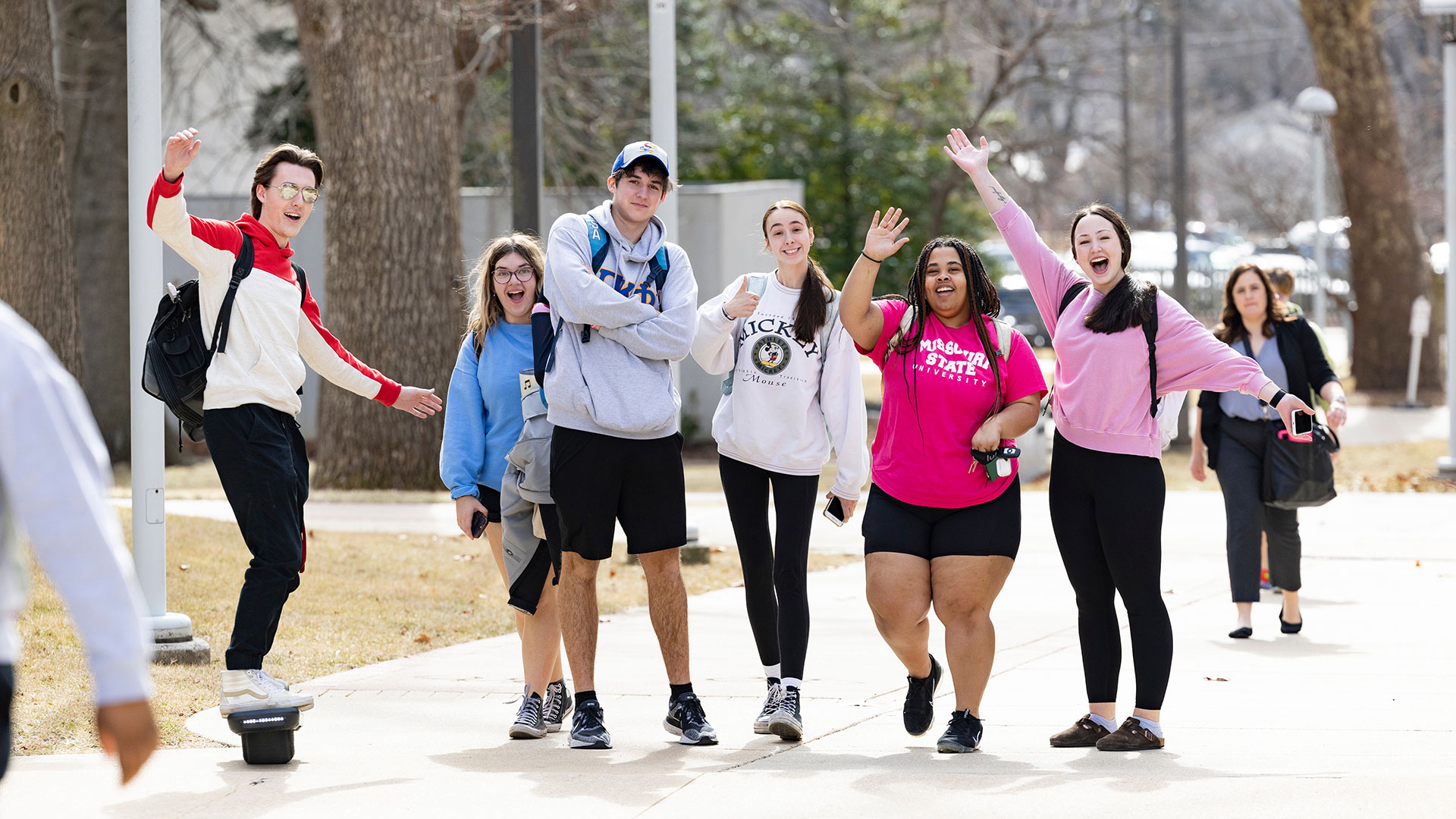 Group of students posing and cheering on the sidewalk.